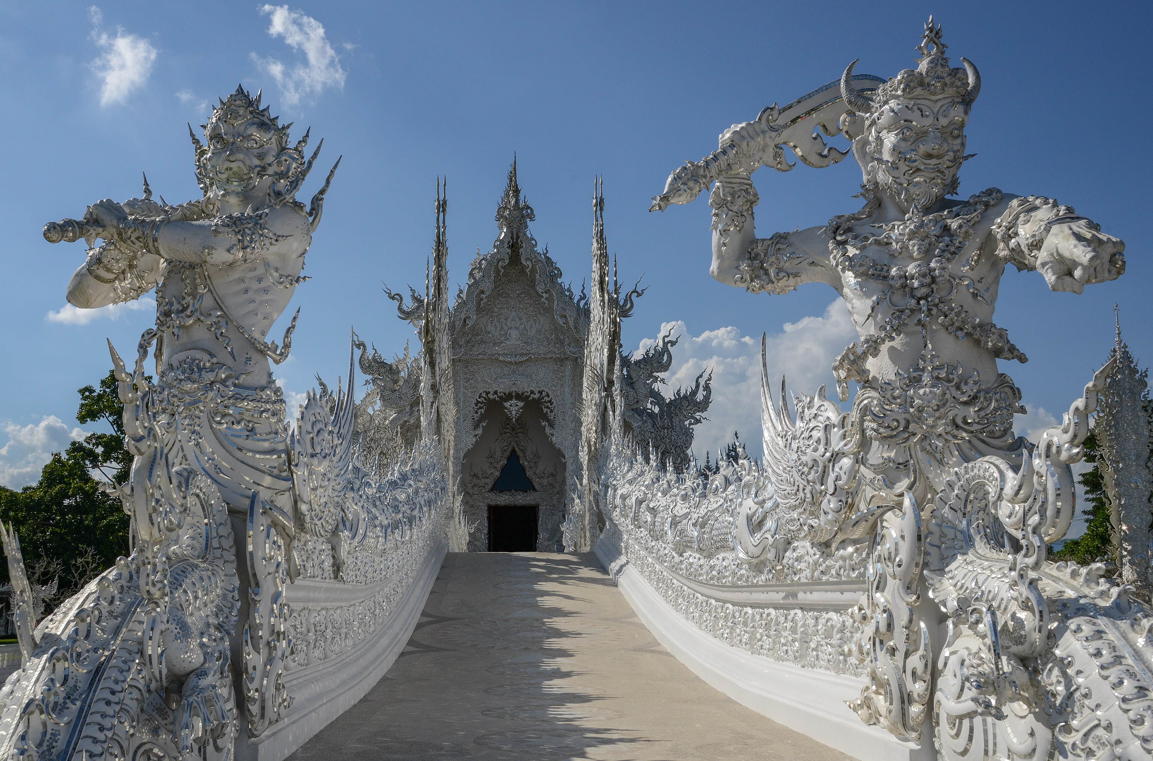 The bridge up to the ubosot, flanked by two white guardian figures at the gate of heaven